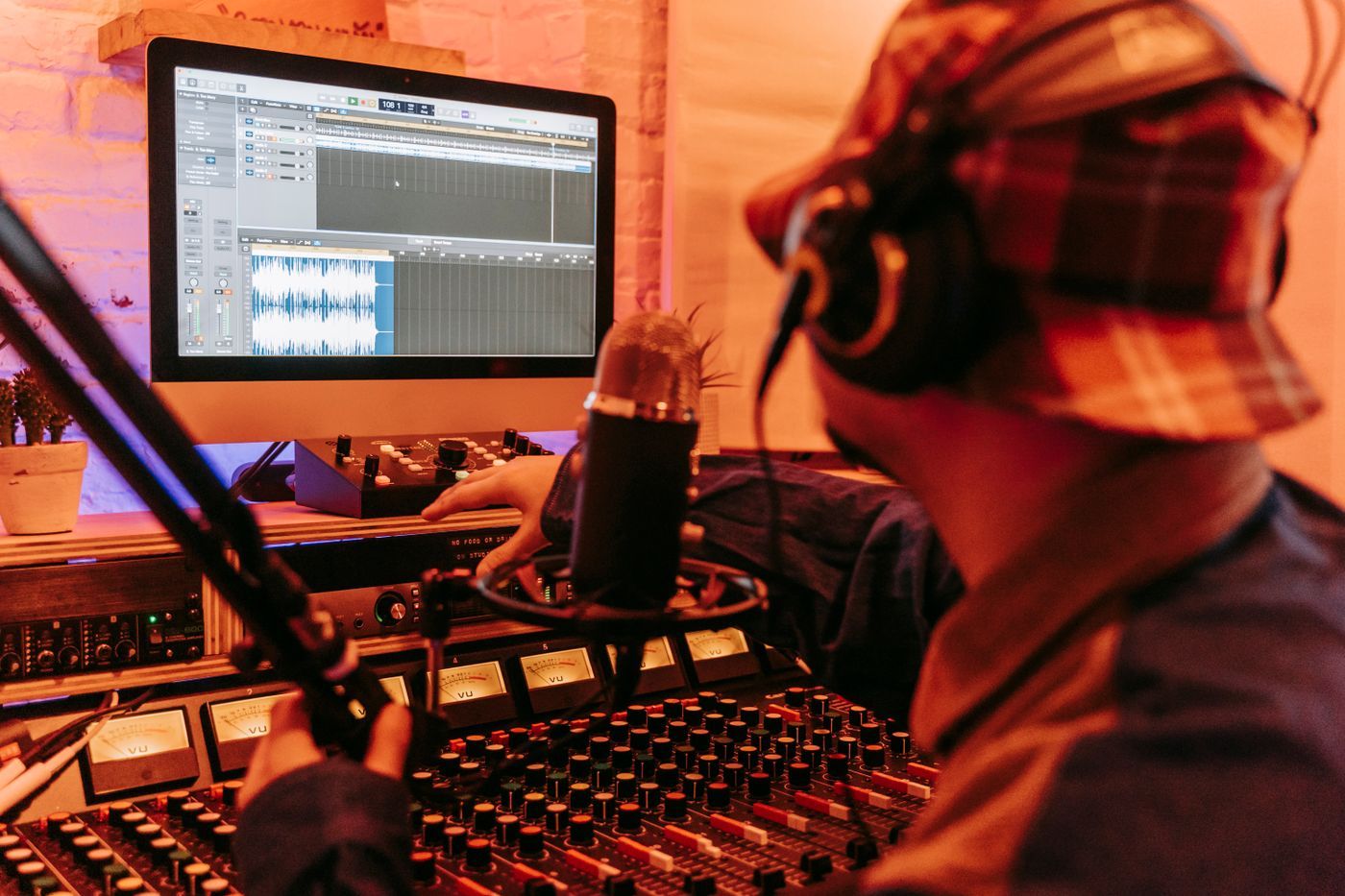 A producer in headphones at his desk, a track open on the screen